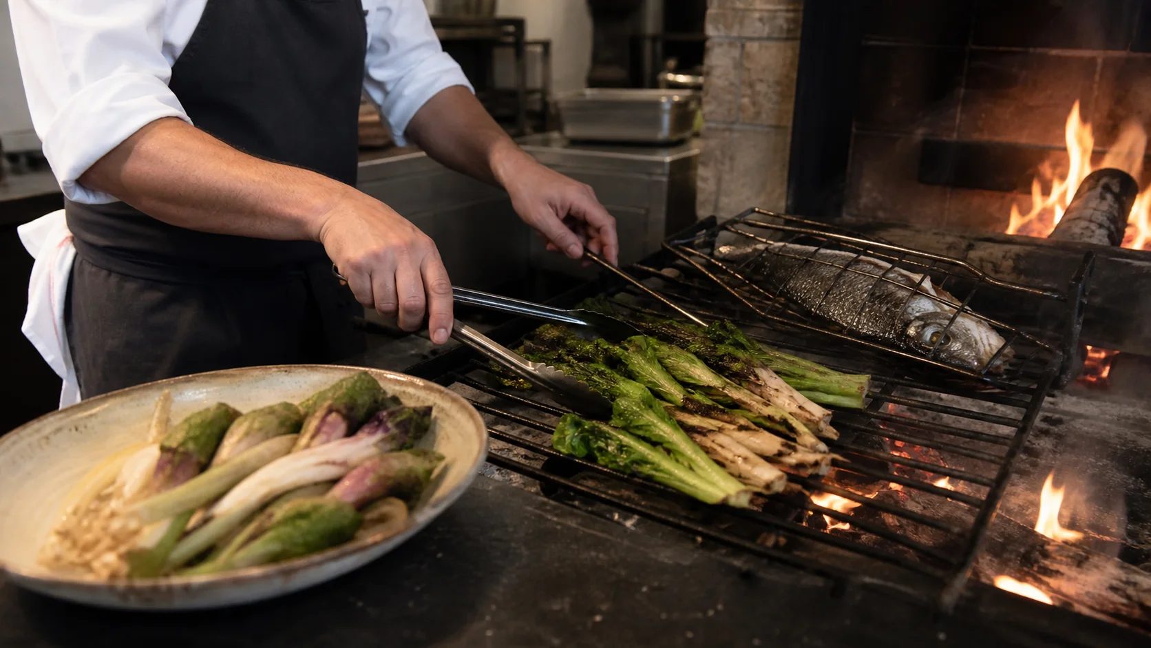 Chef tending fish and vegetables over the live-fire hearth